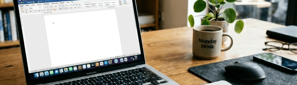 Laptop with project management app open beside 2024 notes notebook on wooden desk